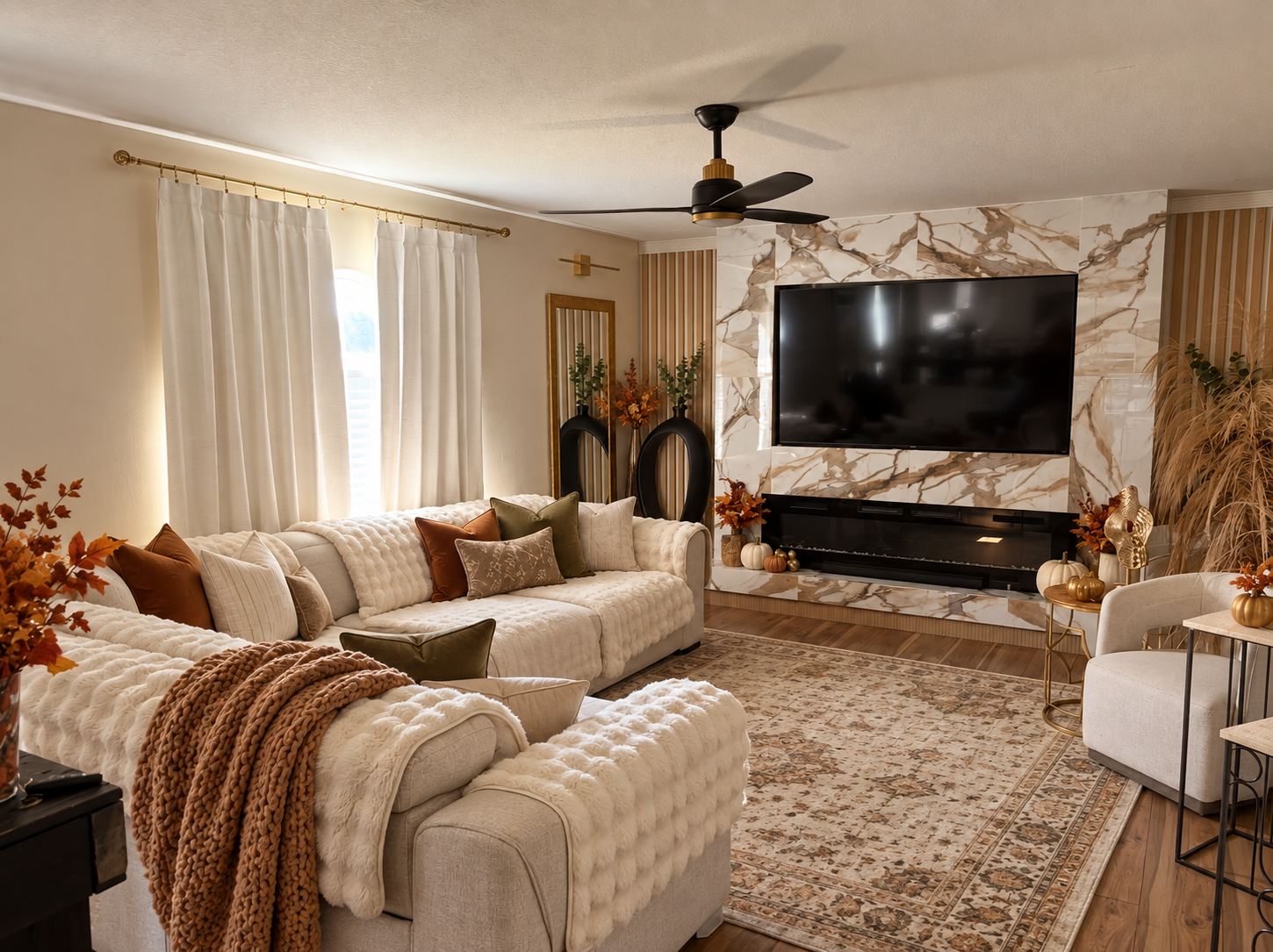 Fall design visualization of Santima Jasper’s living room with cream seating, a warm patterned rug, rust and olive pillows, pumpkins, and a cozy knit throw.
